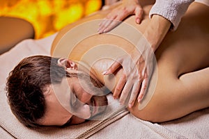 Female masseur does back massage to the young man in spa beauty salon