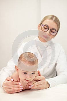 Female masseur doing baby massage for infant baby child.