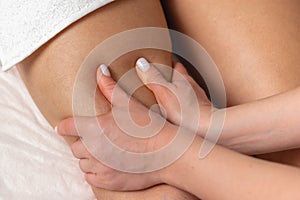 Female masseur hands making thigh massage close-up, body care in spa salon for young woman, beautiful girl enjoying treatment