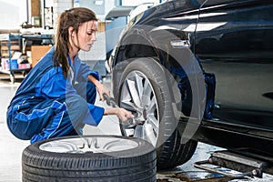 Female Mechanic Changing Car Tire At Automobile Shop