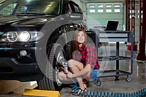 Female mechanic changing tire with air impact wrench