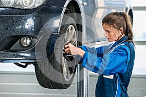 Female Mechanic Changing Tire From Suspended Car