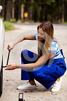 Female mechanic changing tire with wheel wrench photo