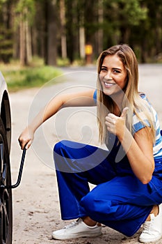 Female mechanic changing tire with wheel wrench photo