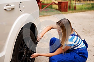 Female mechanic changing tire with wheel wrench photo