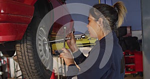 Female mechanic changing tires of the car using a wheel wrench at a car service station