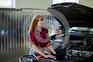 Female mechanic in checked shirt at work. auto service station.