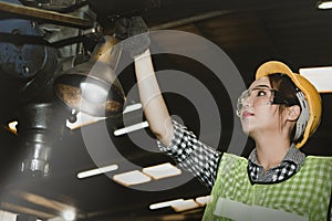 Female mechanic controls the operation of an electric drill. A female worker working in a factory.
