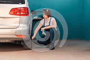 A female mechanic inspects a car tire in an auto repair shop. The concept of women& x27;s work in male professions