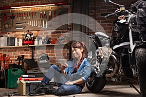 Female mechanic relaxing in a motorbike workshop