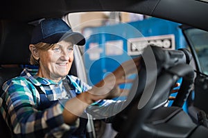 Senior female mechanic repairing a car in a garage.