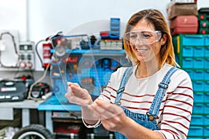 Female mechanic with security glasses touching transparent tablet