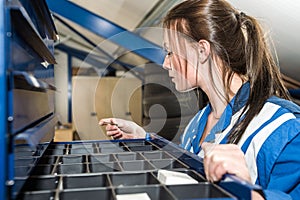 Female Mechanic Selecting From Drawer At Garage