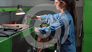 A female mechanic turner processes steel parts in a production workshop. The concept of an industrial worker in a