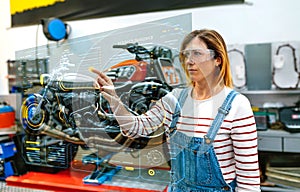 Female mechanic using hud panel screen with augmented reality hologram to review motorcycle