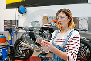 Female mechanic using transparent digital tablet with motorcycle diagnosis app