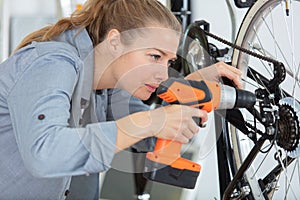 female mechanic working on bicycle chain using cordless screwdriver photo