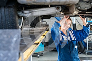 Female Mechanic Working Under Car On Hydraulic Lift
