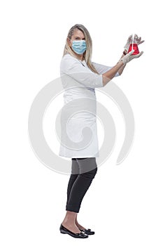 Female medic in a protective mask looking at the liquid in the flask