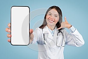 Female medic in white coat, call me gesture and blank phone screen