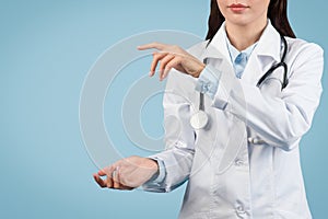 Female medic in white coat holds invisible object