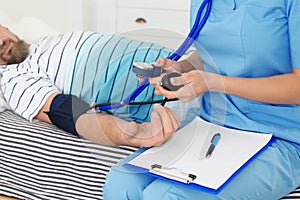 Female medical assistant measuring male patient blood pressure