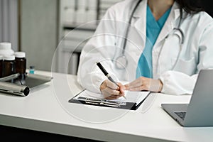 female medical doctor's hands write a note and use tablet working.