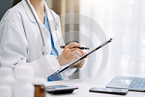 female medical doctor's hands write a note and use tablet working. Doctor's working place.