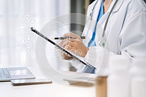 female medical doctor's hands write a note and use tablet working. Doctor's working place.