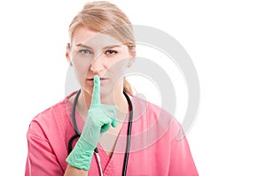 Female medical nurse showing sush or silent gesture