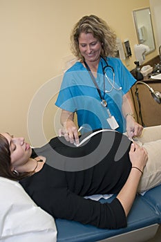 Female medical professional with measuring pregnant woman