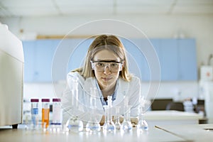 Female medical or scientific researcher looking at a flasks with solutions in a laboratory