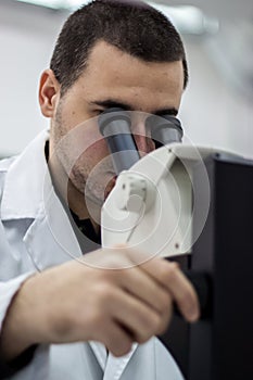 Female medical or scientific researcher man doctor looking through a microscope in a laboratory. Young scientist doing some