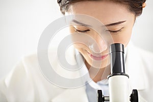 Female medical or scientific researcher watching the microscope