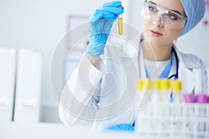 A female medical or scientific researcher or woman doctor looking at a test tube of clear solution in a laboratory