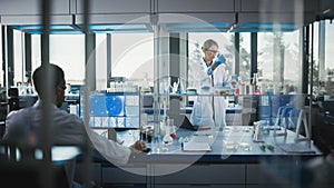 Female Medical Scientist Wearing White Coat and Safety Glasses uses Micropipette while Examining T