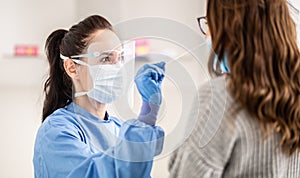 Female medical staff worker wearing protective equipment takes sample from nose of a patient to antigen test for coronavirus