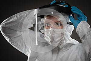 Female Medical Worker Wearing Protective Face Mask and Gear Against Dark Background