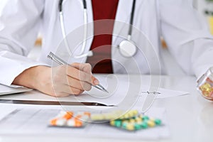 Female medicine doctor fills up prescription form to patient closeup. Panacea and life save, prescribe treatment, lega photo