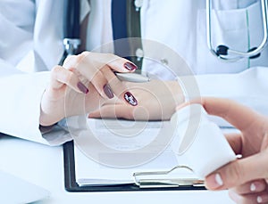 Female medicine doctor hand hold silver pen and points to a jar of pills in patient`s hand.Young doctor talks to patient