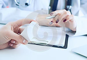 Female medicine doctor hand hold silver pen and points to a jar of pills in patient`s hand.Young doctor talks to patient