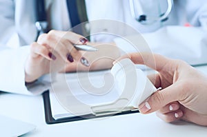 Female medicine doctor hand hold silver pen and points to a jar of pills in patient`s hand.Young doctor talks to patient