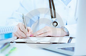 Young female medicine doctor hand holding silver pen writing something on clipboard closeup.