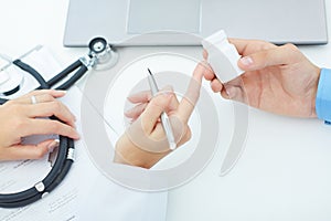 Female medicine doctor hands hold jar of pills and explain the patient how to use daily dose of pills.