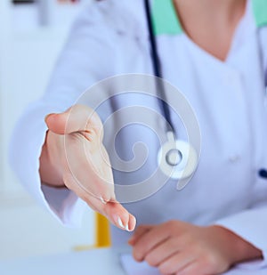 Female medicine doctor offering hand for handshake close up. Partnership and trust concept.