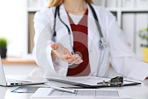 Female medicine doctor offering helping hand in office closeup. Physician ready to examine and save patient. Friendly photo