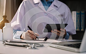 Female medicine doctor, physician or practitioner in lab room writing on blank notebook and work on laptop compute.