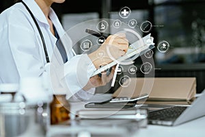 Female medicine doctor, physician or practitioner in lab room writing on blank notebook and work on laptop computer with medical