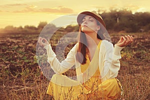 Female meditate sitting on a deadwood autumn field.