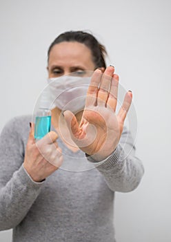 Woman wear medical mask and hold blue sanitizer spray photo